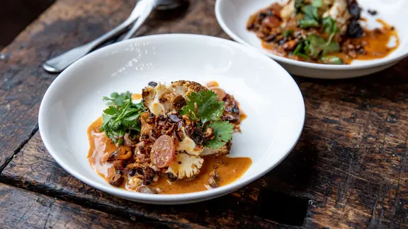 Ein Teller mit Blumenkohl-Curry, garniert mit frischen Kräutern.