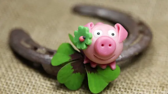Ein Glückschweinchen aus Marzipan, ein Hufeisen und ein vierblättriges Kleeblatt