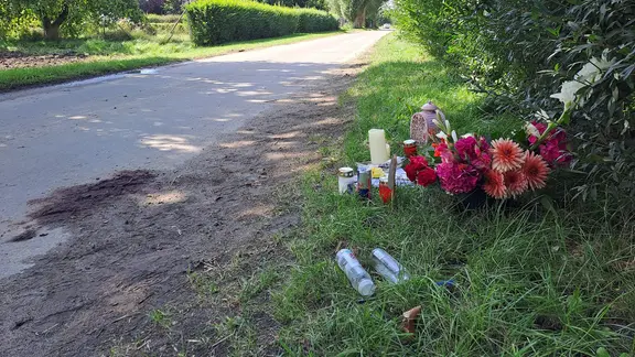 Trauerkerzen und Blumen liegen am Wegrand.