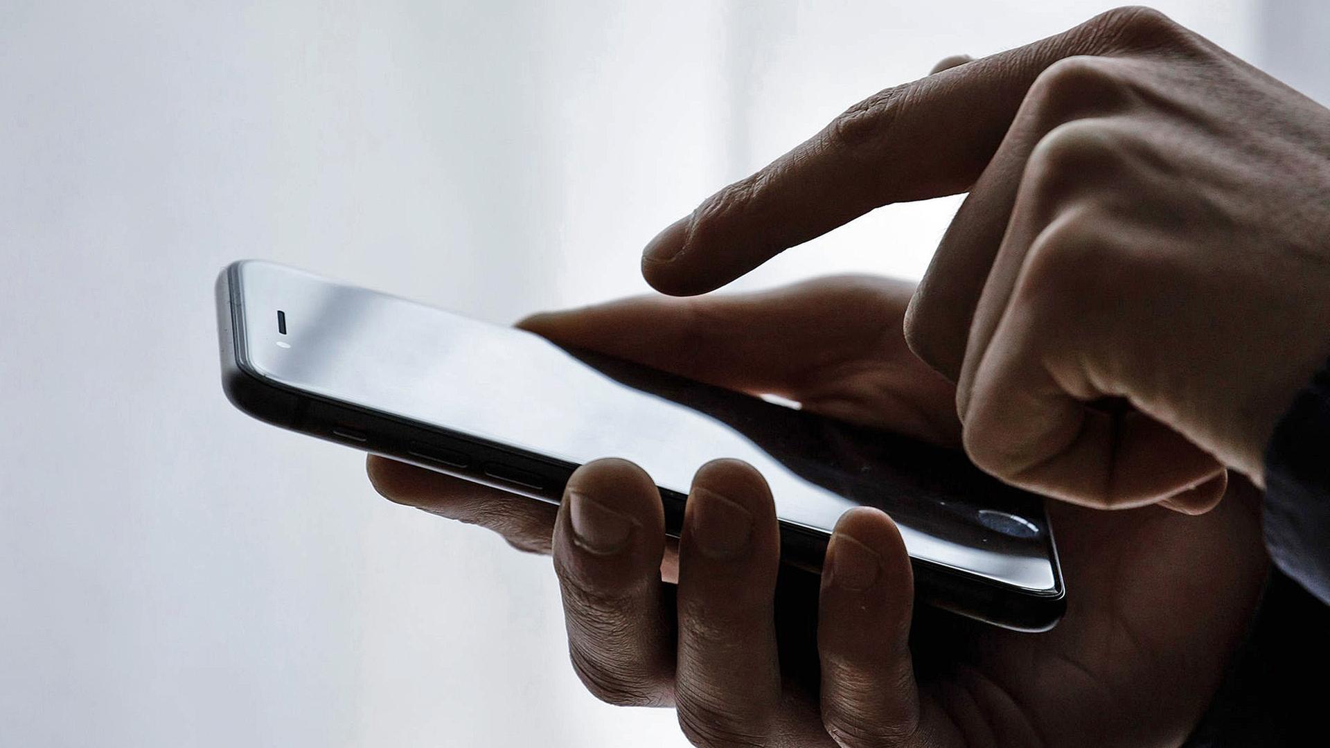 Eine Person hält ein Smartphone in der Hand.  | picture alliance / photothek | Thomas Trutschel, Thomas Trutschel