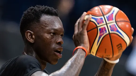 National player Dennis Schröder holds a basketball in his hands.