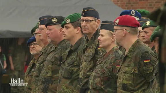 Reservistinnen und Reservisten der Bundeswehr stehen bei einem Gelöbnis mit Tarnjacken in Reihen zusammen.