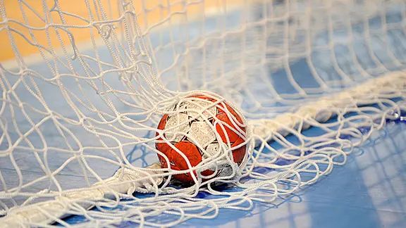 Ein Handball liegt im Tornetz.