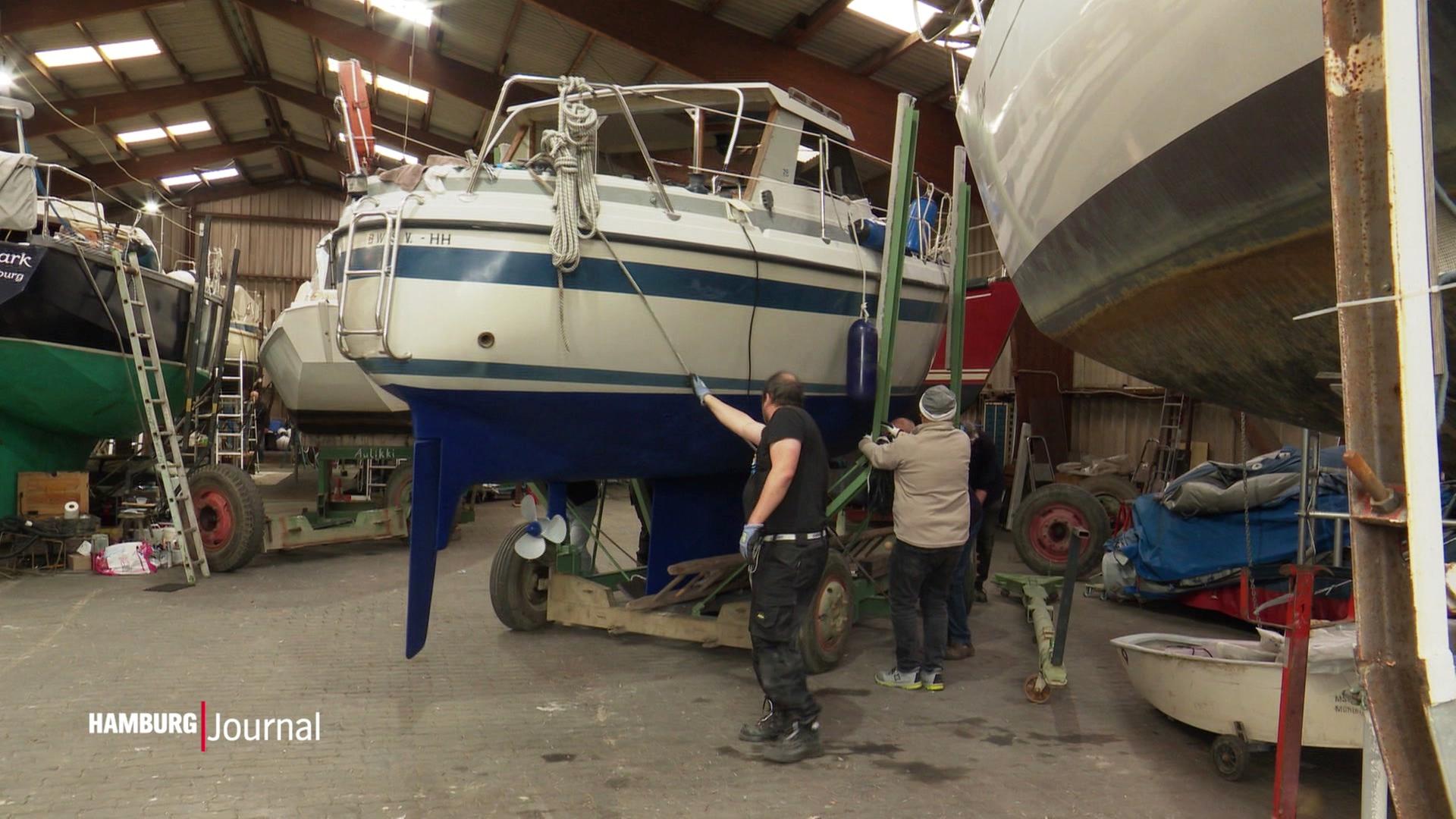 Ein Boot wird aus einem großen Lager herausgerollt. | Screenshot