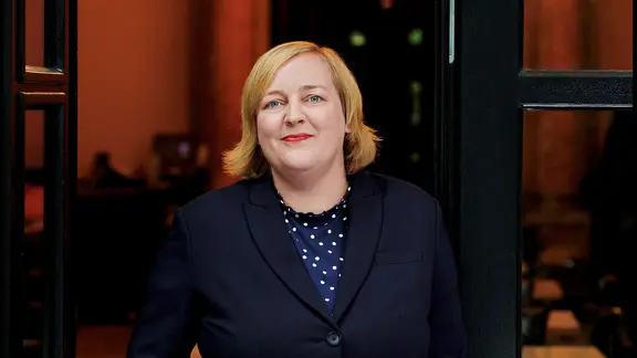 Μια γυναίκα με ξανθά μαλλιά και σκούρο μπλέιζερ φαίνεται φιλική στην κάμερα | Gunter Happy Μια γυναίκα με ξανθά μαλλιά και σκούρο μπλέιζερ φαίνεται φιλική στην κάμερα