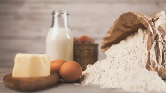 Grundzutaten für das Backen auf einem Tisch: Milch, Butter, Eier und Mehl