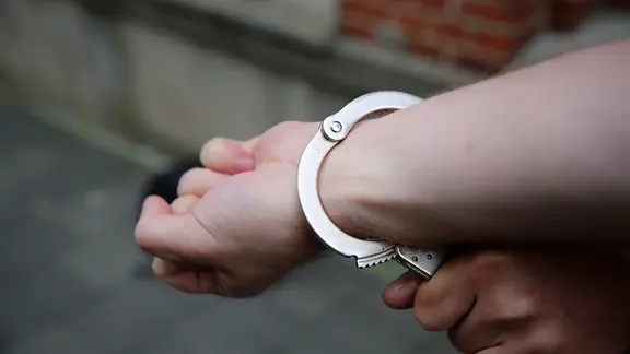 Anwohner wurden auf den mutmaßlichen Täter aufmerksam. Er konnte geschnappt werden. | NDR, Pavel Stoyan Ein Polizist sichert Hand eines Mannes mit Handschellen.