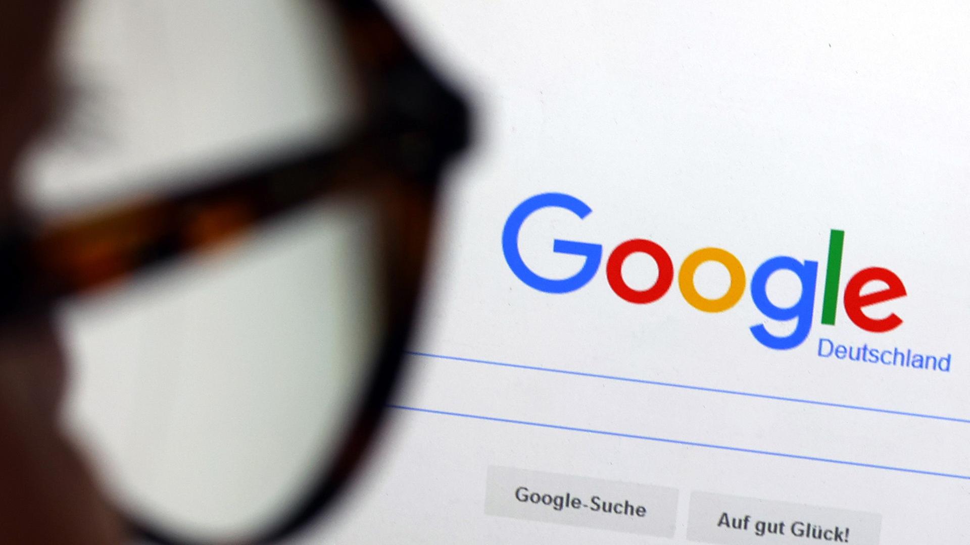 Die Seite der Suchmaschine von Google ist hinter einer Frau mit Brille zu sehen. | picture alliance/dpa | Karl-Josef Hildenbrand, Karl-Josef Hildenbrand
