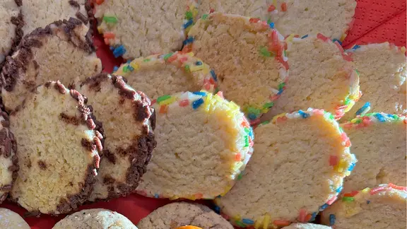 Mehrere Kekstaler, die jeweils mit bunten Streuseln ummantelt sind. 