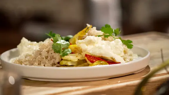 Ofengemüse mit Vollkornreis und Hüttenkäse angerichtet auf einem Teller.