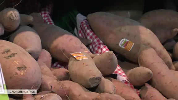 Süßkartoffeln liegen in einem Supermarktregal.