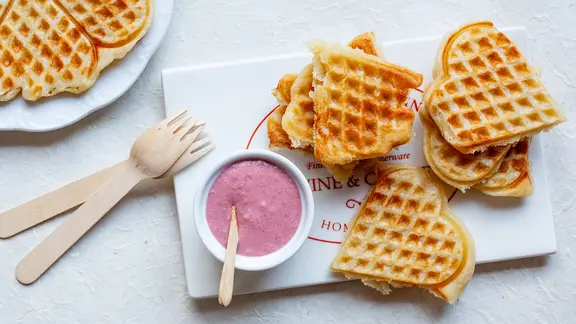 Zwei Teller mit Vollkornwaffeln und ein Schälchen Sauerkirschensauce stehen auf dem Tisch.