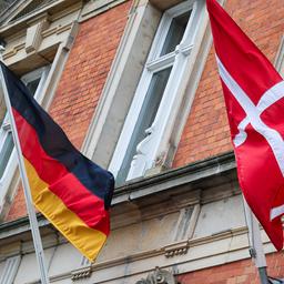 Eine deutsche und eine dänische Flagge wehen über dem Eingang eines Hotels nebeneinander.