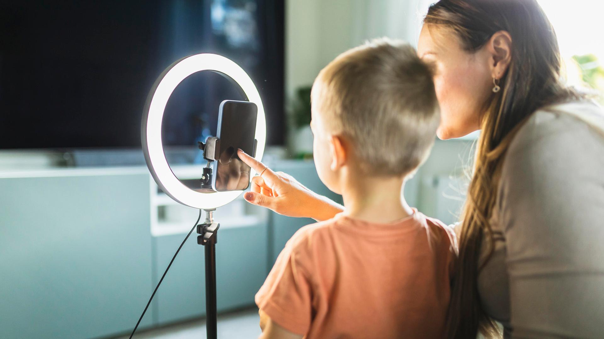 Eine Mutter beim Streamen mit ihrem Sohn mit einem Smartphone und Ringlicht. | picture alliance / Westend61, Diego Martin