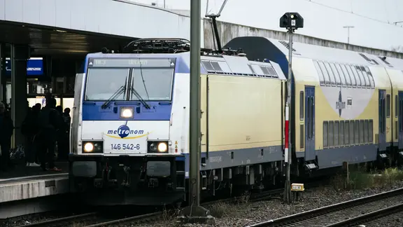 Ein Zug der Metronom Eisenbahngesellschaft steht auf einem Gleis im Bahnhof.