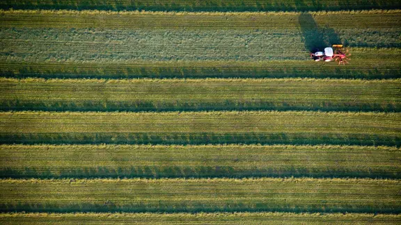 Zu sehen ist ein Acker aus der Vogelperspektive, über den ein Traktor fährt