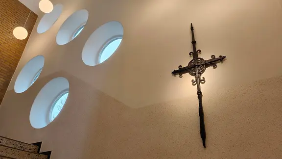 Ein Kreuz hängt in einer Kirche.