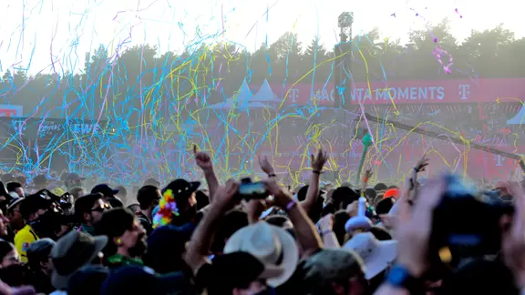 Viele Menschen im Publikum des Outdoorfestivals Hurricane, von oben fällt Faden-Konfetti in vielen Farben