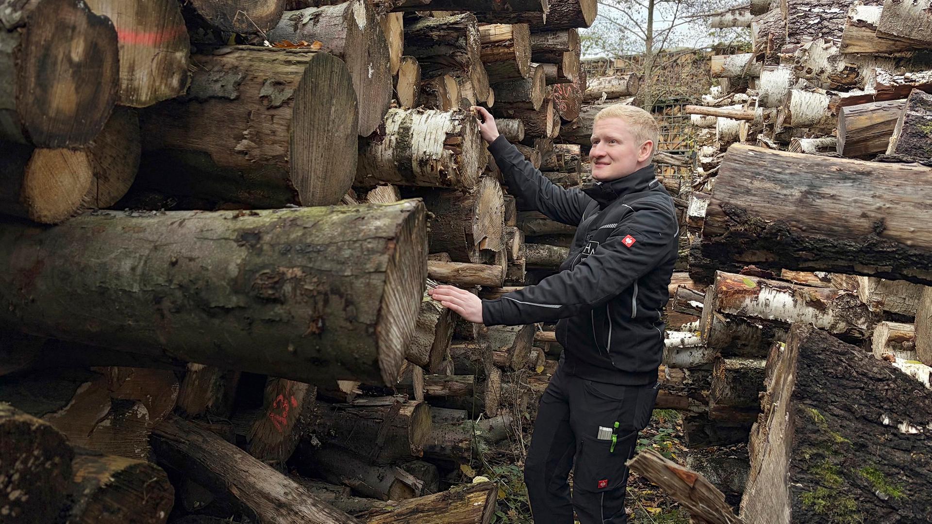 Henrik Alswede vor einem Stapel Baumstämme. | NDR/Bärbel Fening