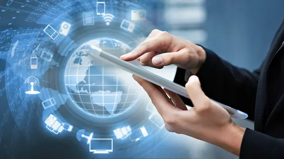 Hände halten ein Tablet-PC, dahinter eine Weltkugel (Bildmontage)