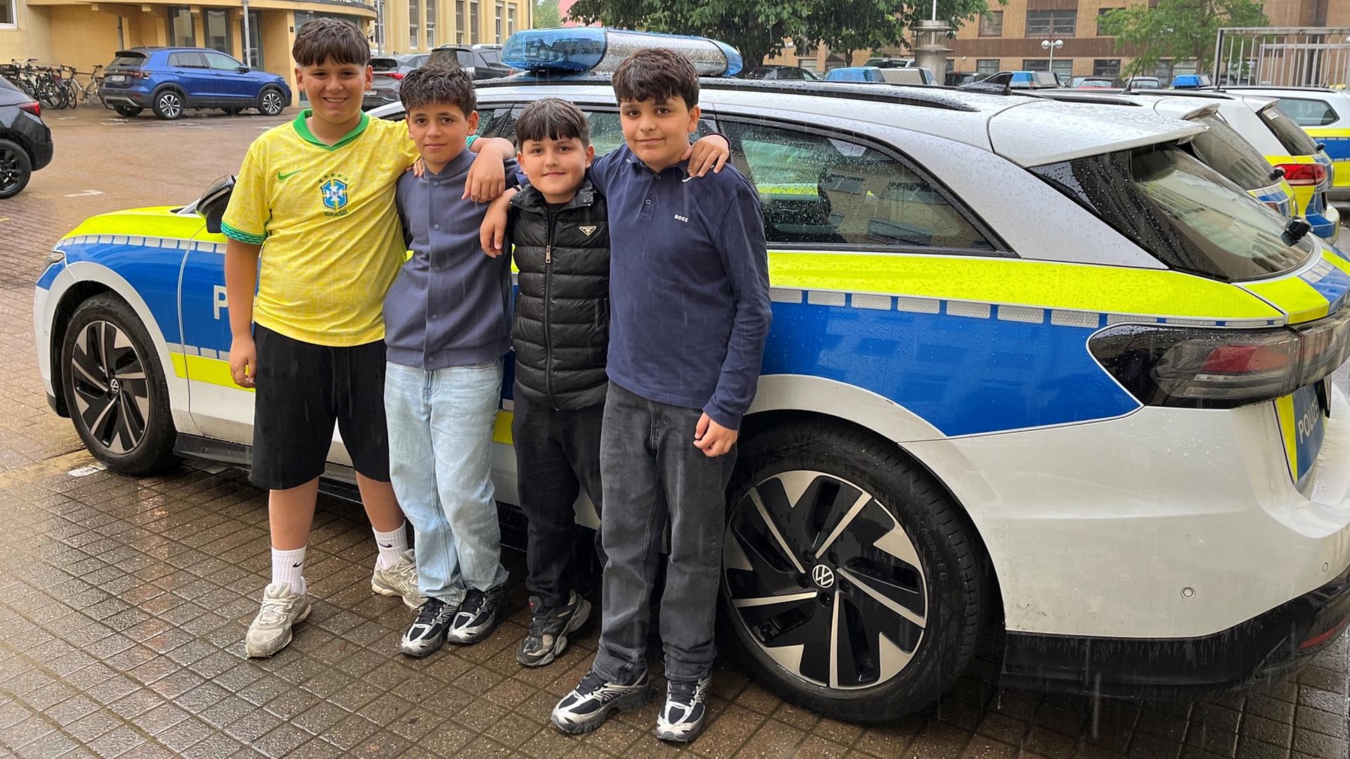 Vier Jungen stehen vor einem Polizeiauto. | Polizei Osnabrück