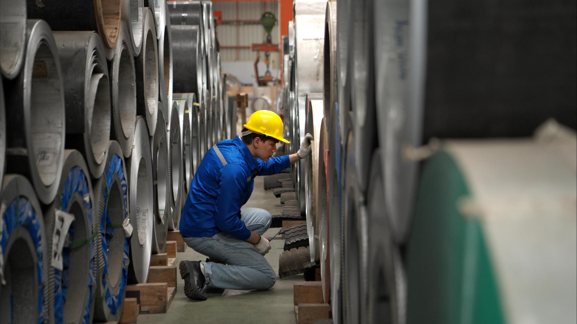 Ein Industriearbeiter kniet zwischen großen Metallrohren | picture alliance / Zoonar | Sunan Wongsa-nga