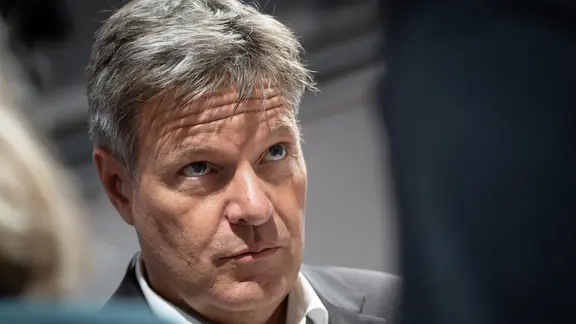 Wirtschaftsminister Robert Habeck steht zwischen zwei Menschen, die von hinten zu sehen sind, und hört ihnen zu. | picture alliance, Chris Emil Janssen Wirtschaftsminister Robert Habeck steht zwischen zwei Menschen, die von hinten zu sehen sind, und hört ihnen zu.