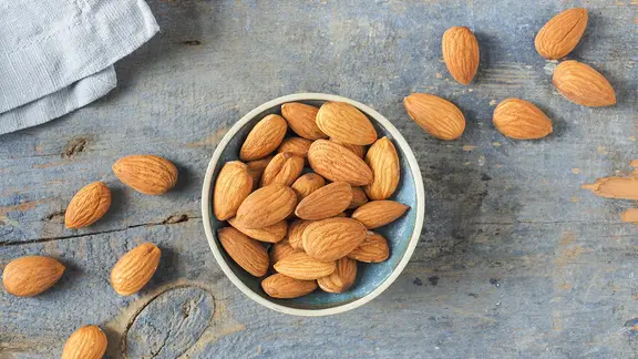 Mandeln in einer kleinen Schale auf einem Holzbrett.