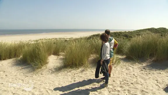 Zwei Personen stehen in einer Dünenlandschaft.