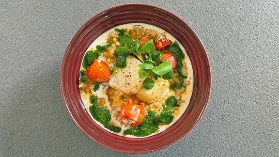 Ein Teller mit Gersten-Eintopf mit Tomaten und Brunnenkresse
