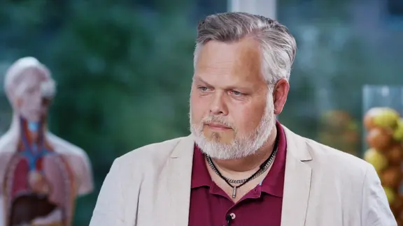 Ein Mann steht vor einer Säule mit Obst.