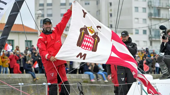 Boris Herrmann auf seiner Malizia in Les Sables-d'Olonne mit der Flagge des Yacht Club de Monaco