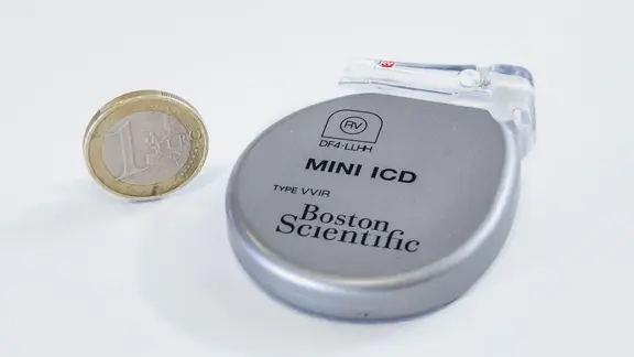 Ein implantierbarer Kardioverter-Defibrillator neben einem Ein-Euro-Stück.
