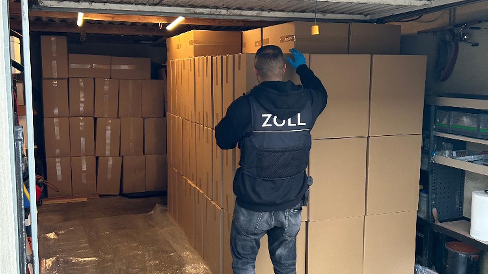 Ein Zoll-Beamter steht in einer Garage vor Kartons. | Zollfahndungsamt Hannover