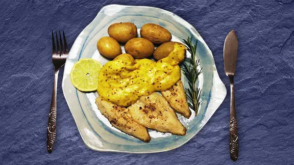 Fischfilets mit Drillingen und einer Zitronenscheibe auf einem Teller