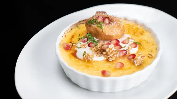 Crème brûlée mit Banane im Backteig auf einem Teller serviert