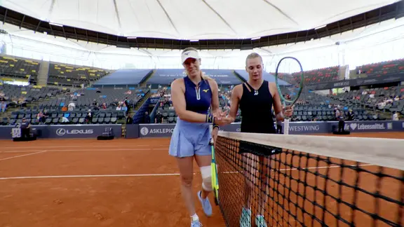 Zwei Tennisspielerinnen geben sich die Hand. 