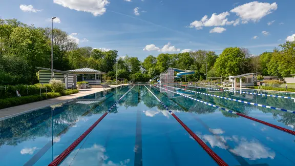 Im Wasser eines Schwimmbeckens spiegeln sich die Wolken.