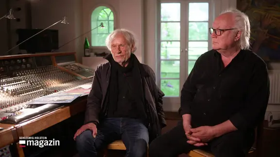 Zwei Bandmitglieder sitzen im Studio.