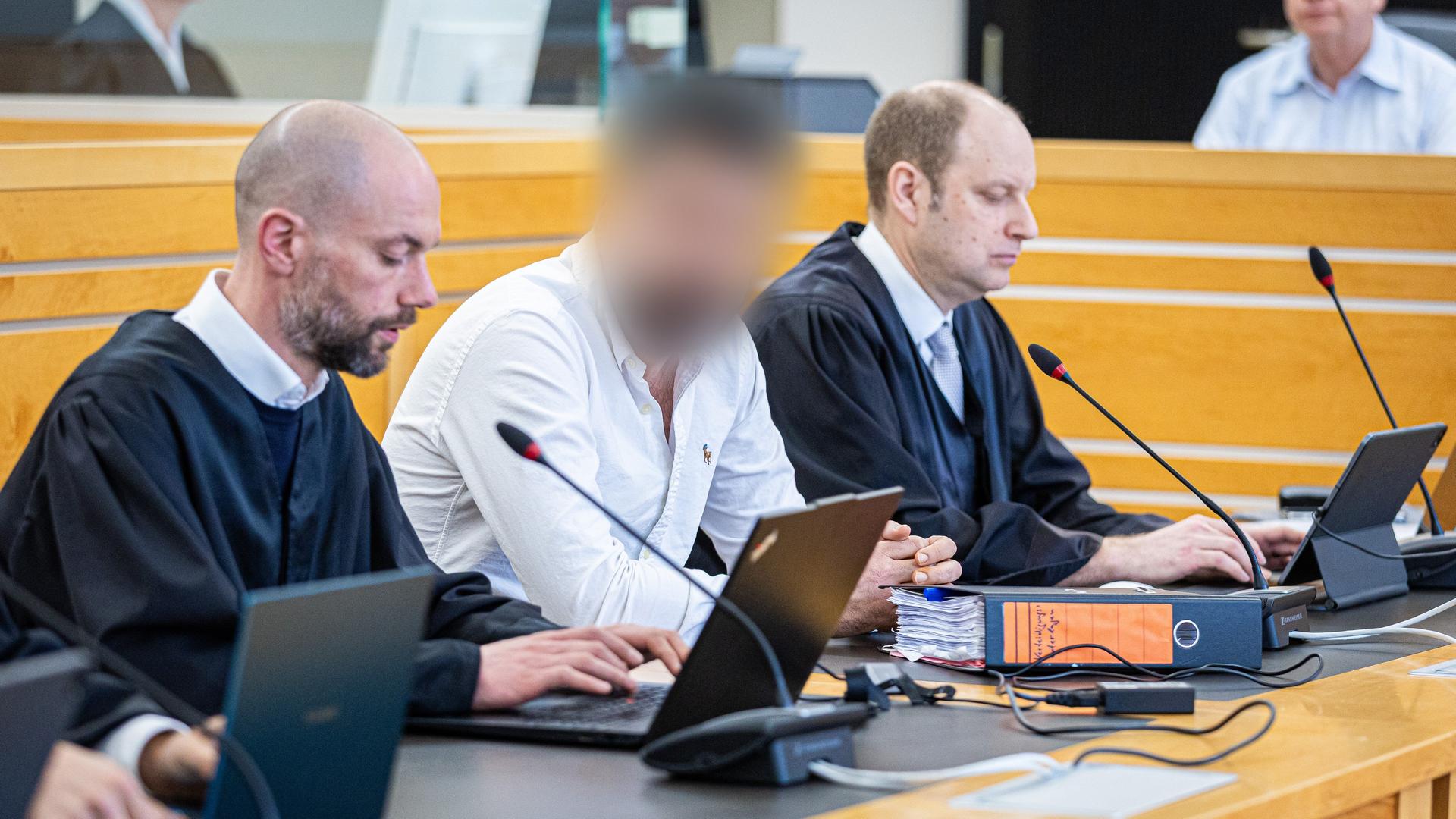Angeklagter in einem weißen Hemd zwischen zwei Anwälten in einem Saal im Landgericht Hannover | picture alliance/dpa | Moritz Frankenberg, Moritz Frankenberg