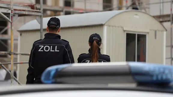 Zwei Zollbeamte auf einer Baustelle.