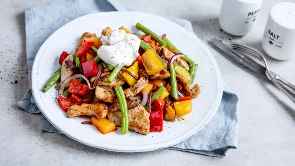 Ein Gericht mit Paprika, Pute und grünen Bohnen auf einem Teller.