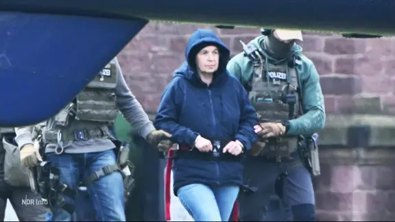 Die mutmaßliche RAF-Terroristin Daniela Klette wird von Polizisten zu einem Hubschrauber geführt.