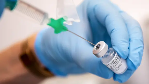 Eine Klinik-Mitarbeiterin zieht einen Covid-19-Impfstoff für eine Impfung auf eine Spritze.