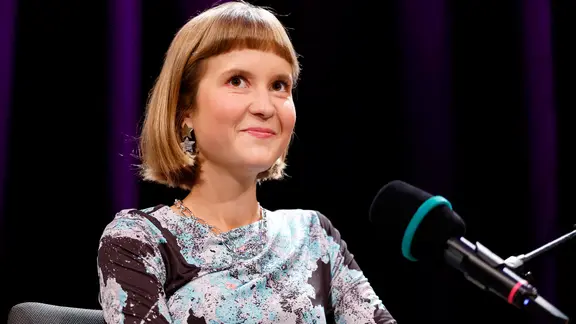 Die Schriftstellerin Caroline Wahl auf einer Bühne, vor ihr steht ein Mikro.