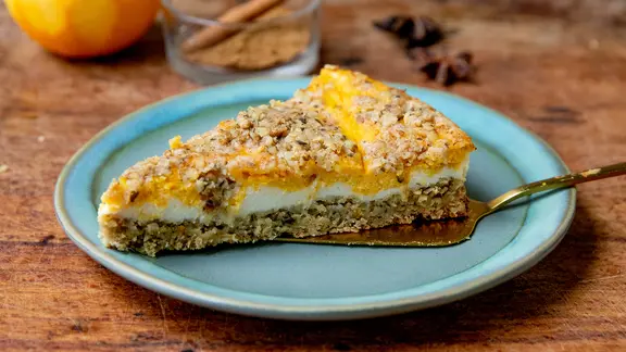 Ein Stück Kürbis-Cheesecake mit Streuseln auf einem Teller.