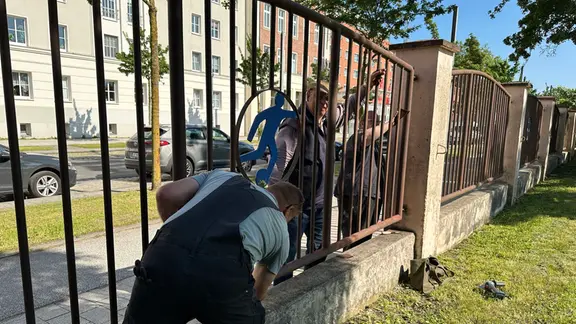 Zwei Männer streichen den Stadionzaun am Frankendamm in Stralsund.