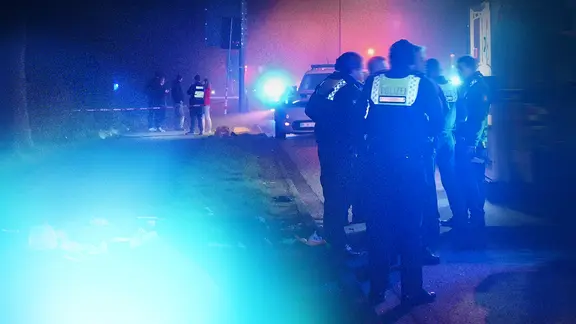 Neblige Nachtaufnahme, Straße in Hamburg-Harburg. Polizisten stehen neben Rettungswagen. Auf der Erde Verpackung vom Rettungskräfteinsatz.