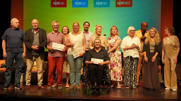 "Vertell doch mal" 2025: Die Gewinner und MOderatoren stehen auf der Bühne.
