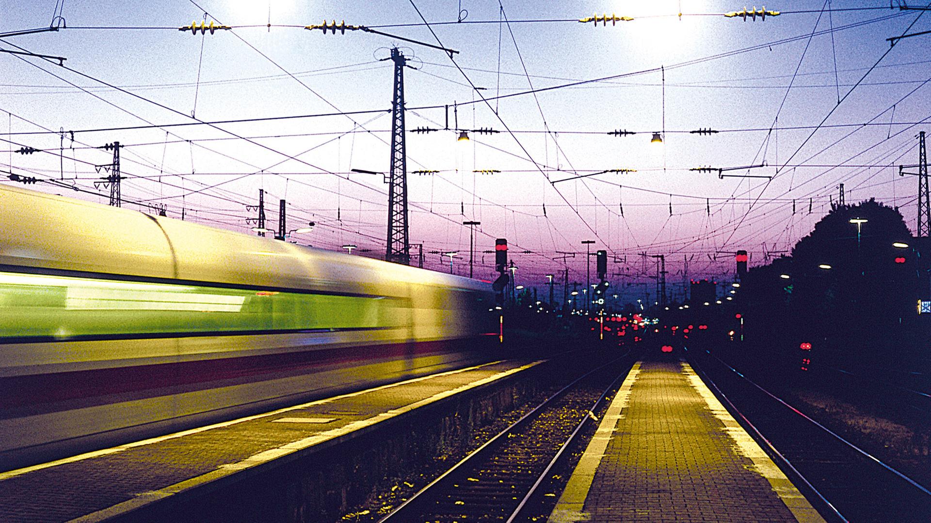 Ein ICE fährt bei Nacht durch einen Bahnhof. | laborant/photocase.de